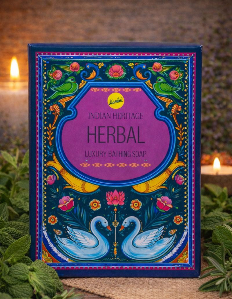 Herbal soap packaging with decorative design on a wooden surface with candles and plants.